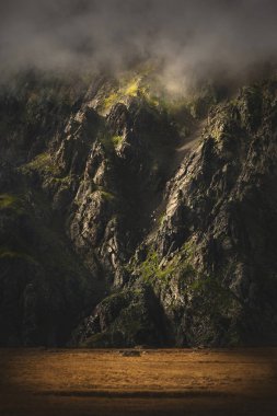 Gün batımı ve alçak bulutlar kayalık yamaç epik görünümünü. Elbrus Kuzey Kafkasya. Kayalık duvar