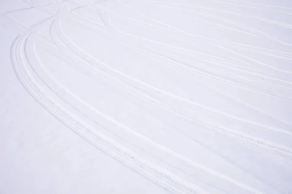 Следы пересекающихся дуг автомобильных шин в свежем снегу — стоковое фото