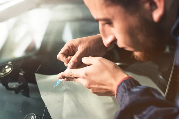 Närbild av en professionell vindrutan reparatör fyller en spricka i glaset med en speciell polymer genom en spruta. Eliminering av sprickor och chips på vindrutor — Stockfoto