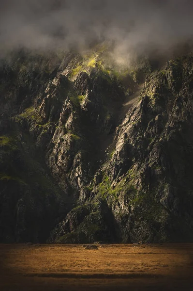 The epic view of the rocky slope in the sunset and low clouds. Elbrus North Caucasus. Rocky wall