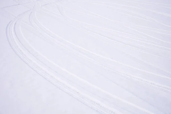 Spuren sich kreuzender Bögen von Autoreifen im Neuschnee lizenzfreie Stockfotos