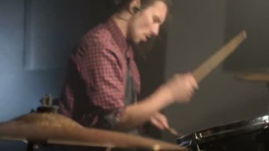 Uzun saçlı davulcular davul kiti karanlık bir odada bir siyah arka plan üzerinde oynamak. Rock müzisyeni. Statik plan. Geniş açı