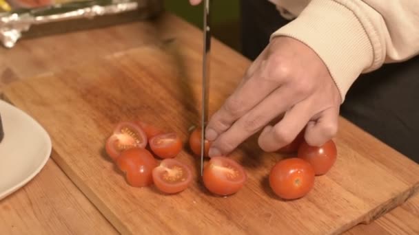 Close-up das mãos de uma menina na cozinha da casa em uma tábua de corte de madeira pequenos tomates cereja. Cozinha caseira — Vídeo de Stock