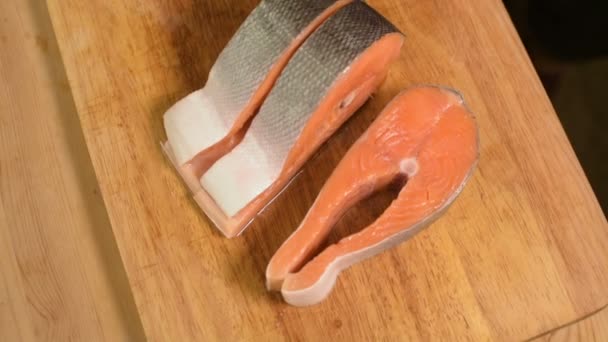 Primer plano lonchas de salmón rebanadas de pescado dietético rojo en una tabla de cortar de madera. Cocina casera. Alimento saludable — Vídeo de stock
