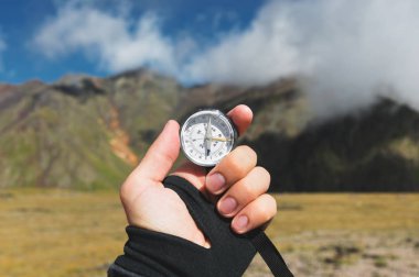 Bakış açısı vurdu. Bir birinci şahıs bakış bir el tutar kayalıklarla hills, epik bir yatay ve bir mavi gökyüzü bulutlu arka planı pusula mans.