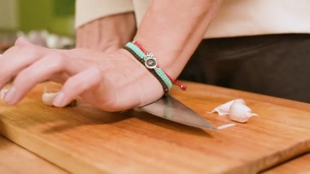 Primer plano de las manos femeninas en casa cocina limpia el ajo de la cáscara. Profundidad superficial del campo — Vídeo de stock