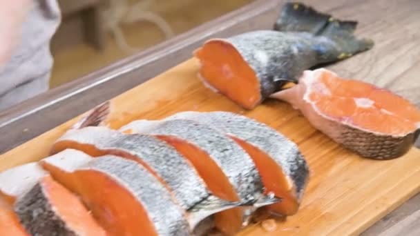 Primer plano de las manos femeninas están cortando con un cuchillo un salmón grande en una mesa de madera de cocina casera — Vídeo de stock