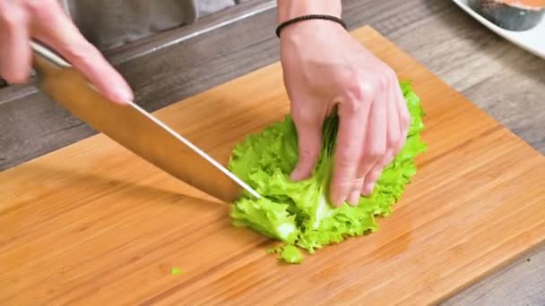 女性手的特写镜头是用沙拉叶切刀 以便在木制切菜板上做沙拉素菜 家庭厨房 健康食品 — 图库视频影像