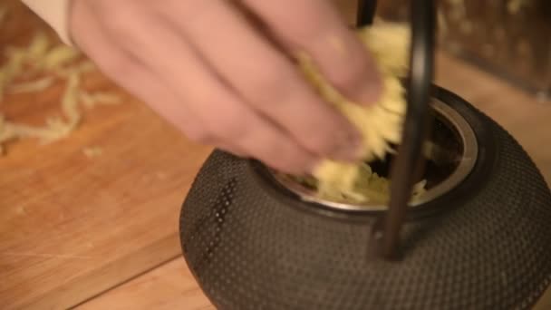 Close-up van vrouwelijke handen vullen de theepot met geraspte gember. De keuken van het huis. Gezonde voeding — Stockvideo