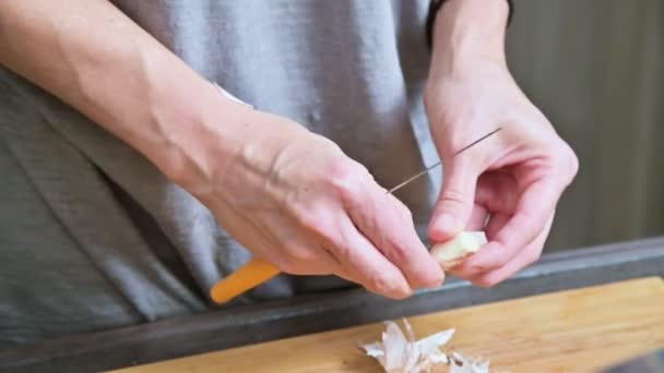 Nahaufnahme von weiblichen Händen in der heimischen Küche reinigen Knoblauch von der Schale. geringe Schärfentiefe — Stockvideo