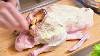 Erkek Close-up hazırlanıyor ördek ya da kaz pişirme için eller. Mayonezli havuç soyunma beyaz. Elma ile Noel yemeği ördek kaz
