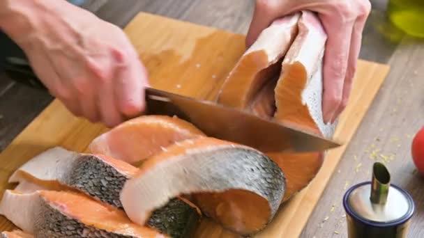 Close-up of female hands are cutting with a knife a large salmon on a wooden table of home cooking — Stock Video