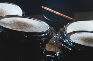 Karanlık bir stüdyo portre görünümünde bir davul seti ve sopaları. Siyah drum varil ile krom trim. Canlı performanslar kavramı