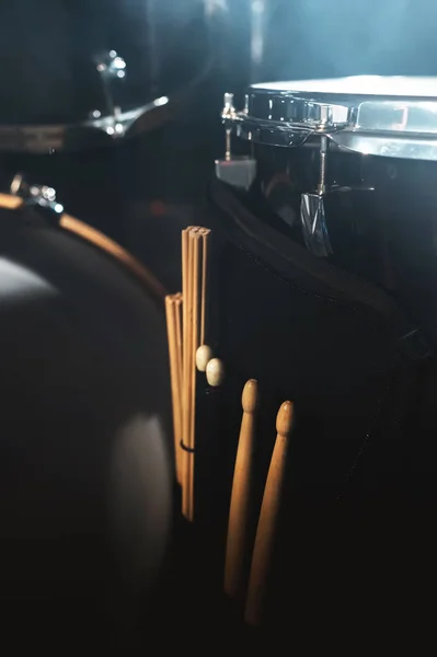 Closeup view of a drum set and Drumsticks in a dark studio. Black drum barrels with chrome trim. The concept of live performances — Stock Photo, Image