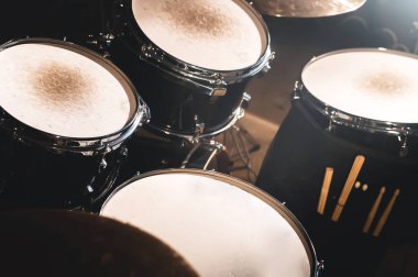 Karanlık bir stüdyo portre görünümünde bir davul seti ve sopaları. Siyah drum varil ile krom trim. Canlı performanslar kavramı