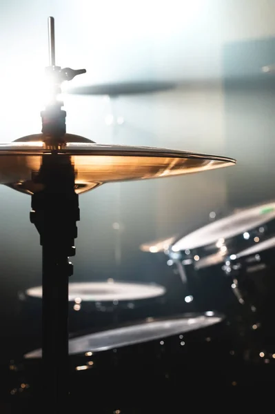 Nahaufnahme eines Schlagzeugs in einem dunklen Raum vor dem Hintergrund des Scheinwerferlichts. atmosphärisches Hintergrundsymbol für das Spielen von Rock- oder Jazz-Drums. Kupferplatten auf kaltem Hintergrund — Stockfoto