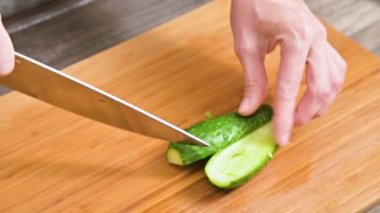 Bir erkek closeup elinde bir bıçak salatalık salatası ahşap kesme tahtası üzerinde yemek pişirmek için kesme. Ev mutfak. Sağlıklı gıda