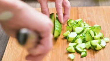 Bir erkek closeup elinde bir bıçak salatalık salatası ahşap kesme tahtası üzerinde yemek pişirmek için kesme. Ev mutfak. Sağlıklı gıda