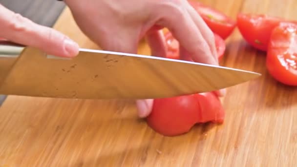 El primer plano de las manos femeninas con un cuchillo está cortando tomates para hacer ensalada en una tabla de cortar de madera. Cocina casera. Alimento saludable — Vídeos de Stock