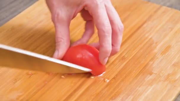 El primer plano de las manos femeninas con un cuchillo está cortando tomates para hacer ensalada en una tabla de cortar de madera. Cocina casera. Alimento saludable — Vídeos de Stock