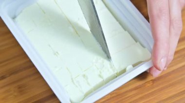 Yunan salatası için küpler halinde beyaz beyaz peynir bir pakette bir bıçak kesim eller Close-up