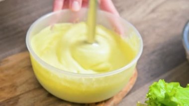 Plastik bir kabın içinde bir blender ile ev yapımı mayonez kırbaçlanan yakın çekim