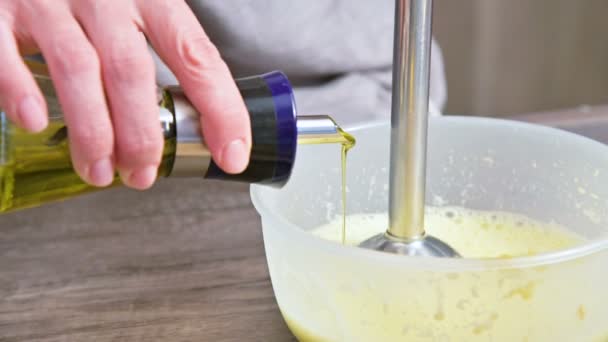 用塑料碗里的搅拌机对自制蛋黄酱的混合物进行特写。橄榄油 — 图库视频影像
