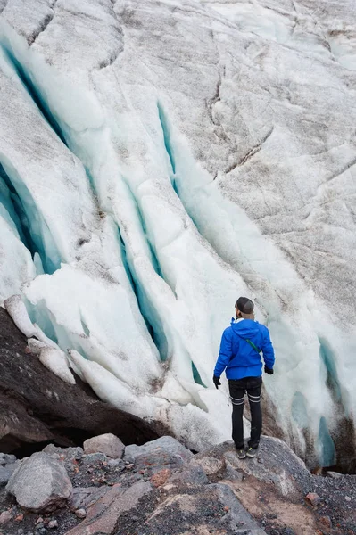 Gezgin bir şapka ve güneş gözlüğü karlı dağların buzul üzerinde duruyor. Gezgin bir doğal ortamda — Stok fotoğraf
