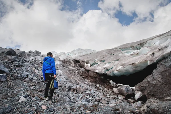 Utazó egy sapka és napszemüveg áll a havas hegyek a gleccser. Utas, a természetes környezet — Stock Fotó