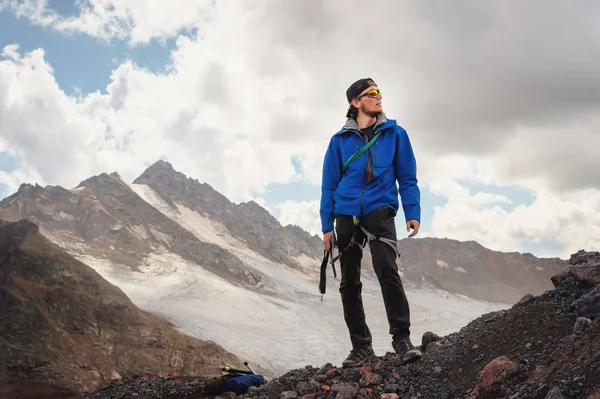Portrét profesionálního průvodce horolezec v čepici a brýle s cepín v ruce proti sněhu-limitován pohoří Kavkaz a pozadí oblohy — Stock fotografie