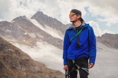 Bir şapka ve güneş gözlüğü bir dağcı gökyüzü arka plan ve Kafkasya karla kaplı dağlar karşı elinde bir buz balta ile profesyonel bir rehber portresi