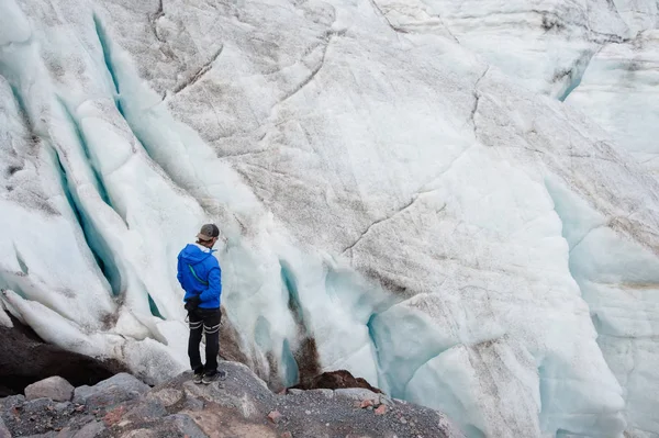 El viajero con gorra y gafas de sol está de pie en las montañas nevadas del glaciar. Viajero en un entorno natural —  Fotos de Stock