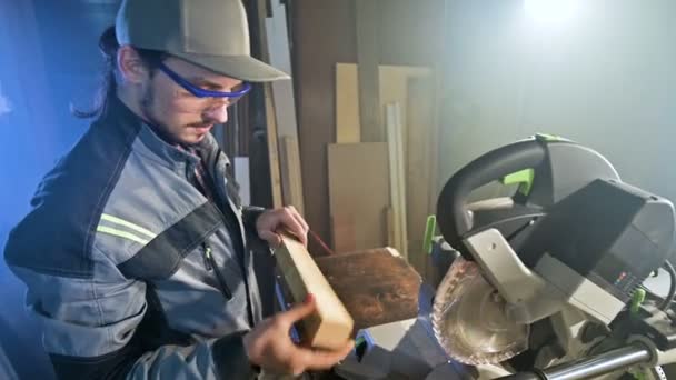 Konzentrierter junger bärtiger Schreiner mit Brille und Mütze prüft das Werkstück auf Tauglichkeit, während er es in den Händen hält und untersucht — Stockvideo