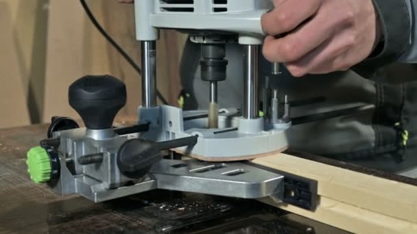 Primer plano de la mano de un carpintero que trabaja con un cortador eléctrico manual en un taller casero. Acabado de piezas de madera — Vídeos de Stock