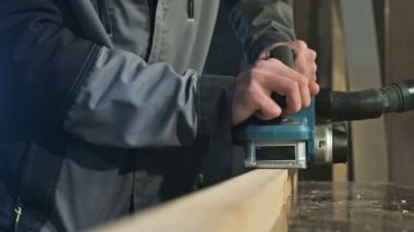 Bir elektrikli uçak eve bir atölyede çalışan bir marangoz El Close-up. Ahşap parçaları bitirme