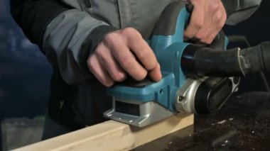 Bir elektrikli uçak eve bir atölyede çalışan bir marangoz El Close-up. Ahşap parçaları bitirme.