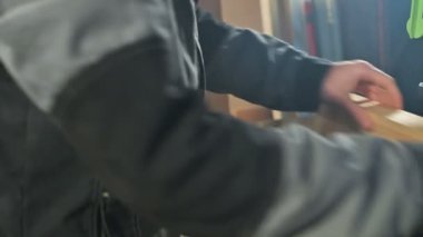 Genç bir marangoz ahşap bir iş parçası bir dairesel testere makinesinde yükler. Home atölye. Acemi işadamı