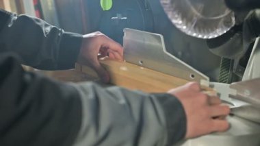 Genç bir marangoz ahşap bir iş parçası bir dairesel testere makinesinde yükler. Home atölye. Acemi işadamı
