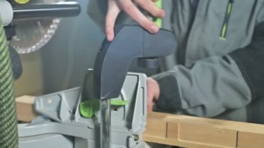 Genç bir marangoz ahşap bir iş parçası bir dairesel testere makinesinde yükler. Home atölye. Acemi işadamı