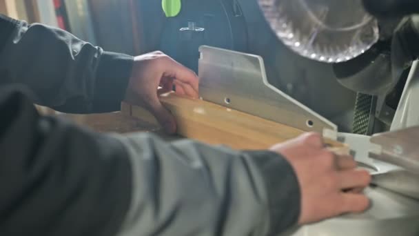 Un joven carpintero instala una pieza de madera en una serradora circular. Taller casero. Empresario novato — Vídeos de Stock