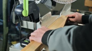 Genç bir marangoz ahşap bir iş parçası bir dairesel testere makinesinde yükler. Home atölye. Acemi işadamı.
