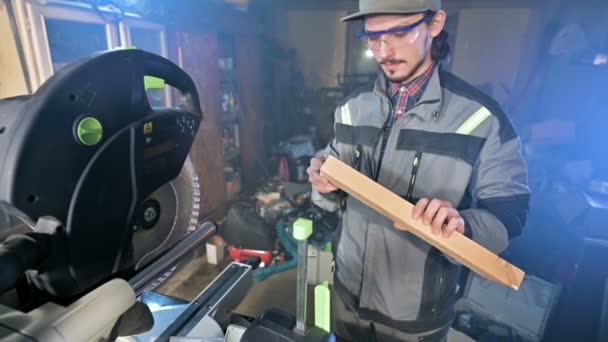 Een jonge timmerman installeert een houten werkstuk in een circulaire zaagmachines machine. Home workshop. Beginnende ondernemer — Stockvideo