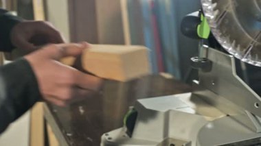 Genç bir marangoz ahşap bir iş parçası bir dairesel testere makinesinde yükler. Home atölye. Acemi işadamı.