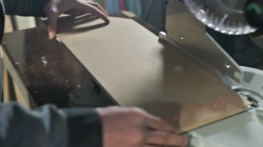 Genç bir marangoz ahşap bir iş parçası bir dairesel testere makinesinde yükler. Home atölye. Acemi işadamı