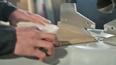 Genç bir marangoz ahşap bir iş parçası bir dairesel testere makinesinde yükler. Home atölye. Acemi işadamı
