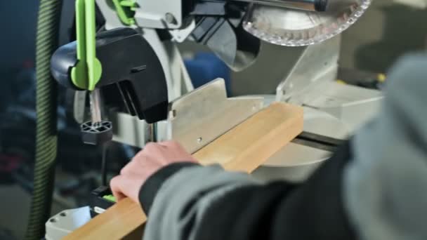 Un tâmplar tânăr instalează o piesă de prelucrat din lemn într-o mașină de tăiat circulară. Atelier de acasă. om de afaceri novice — Videoclip de stoc