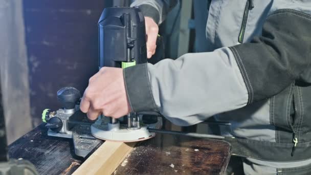 Primer plano de la mano de un carpintero que trabaja con un cortador eléctrico manual en un taller casero. Acabado de piezas de madera — Vídeos de Stock