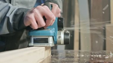 Bir elektrikli uçak eve bir atölyede çalışan bir marangoz El Close-up. Ahşap parçaları bitirme.