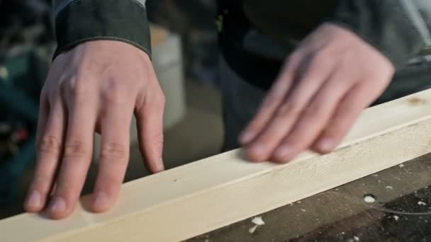 Γκρο πλαν ενός χεριού αρσενικό ξυλουργοί ελέγχοντας την ομαλότητα και την καταλληλότητα του μια ξύλινη σανίδα, μετά την επεξεργασία — Αρχείο Βίντεο