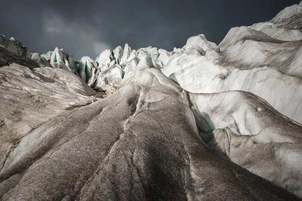 Yakın çekim, buz ve siyah çamur buzulun üzerinde bulunan derin mavi bir çatlak çatlak. Geniş açı ve dramatik gökyüzü — Stok fotoğraf